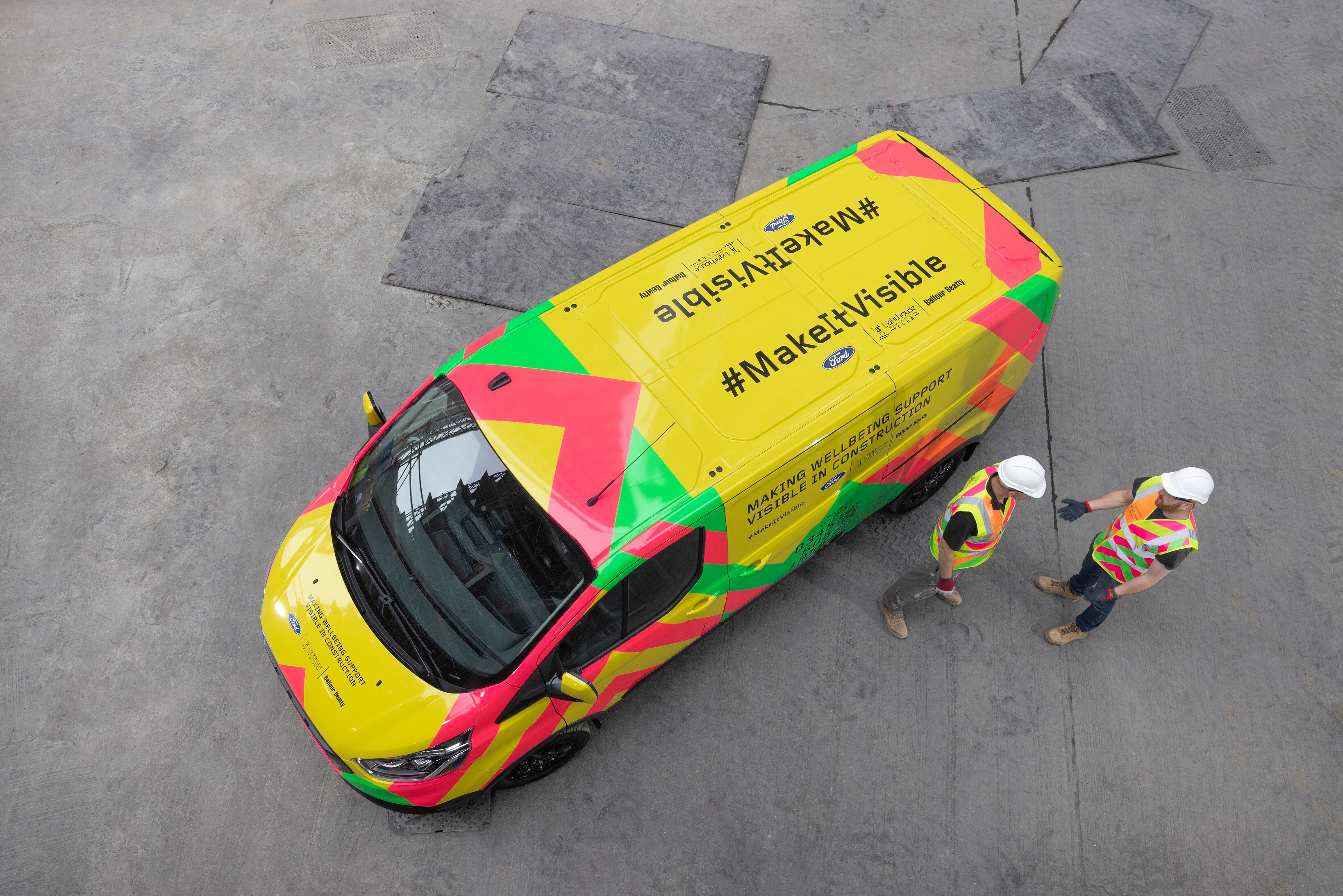 A top down image of a bright yellow van with two hardhat workers
